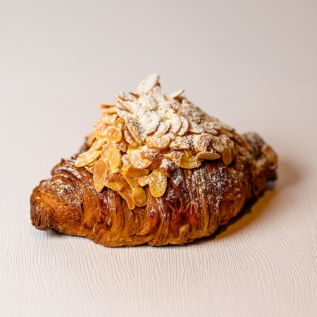 Almond Croissant Flaky croissant dough soaked in simple syrup, filled with Marzipan and garnished with fresh Almonds